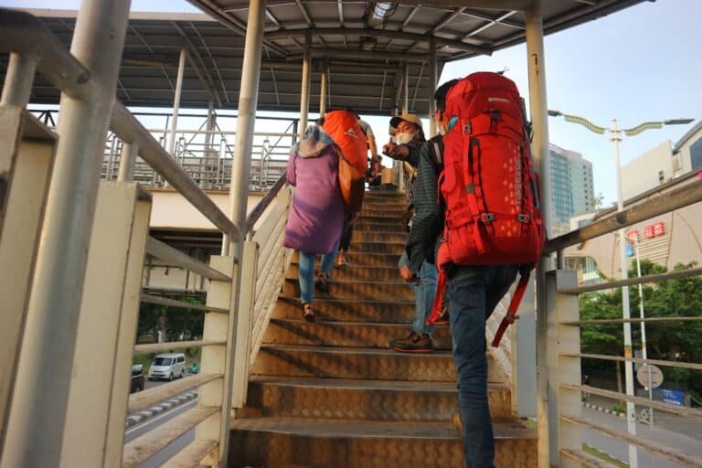 People are walking up stairs with heavy backpacks.